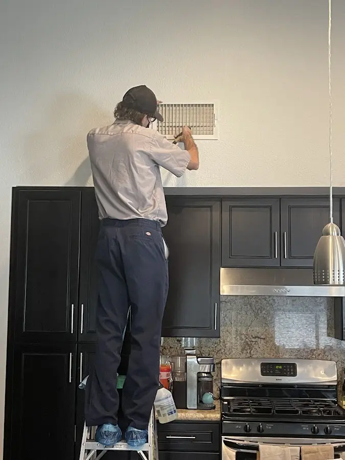 Technician inspecting an air vent during HVAC service in Clinton